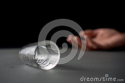 Hand drunk lying empty glass of vodka or alcoholic drink Stock Photo