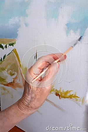 Hand of an elderly person paints a picture with a brush Stock Photo