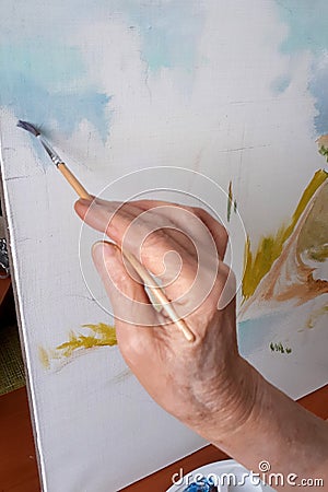 Hand of an elderly person paints a picture with a brush Stock Photo