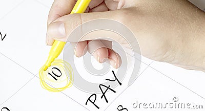 Hand encircles a date on a calendar with text Pay yellow felt-tip pen Stock Photo