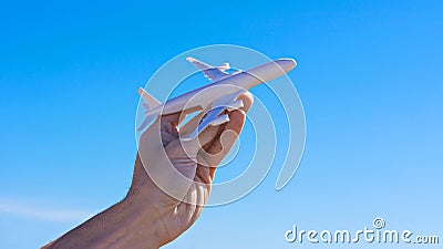 Hand with face aircraft against blue sky. Ban of flights is suspended. Countries open borders, open flights, travel boom Stock Photo