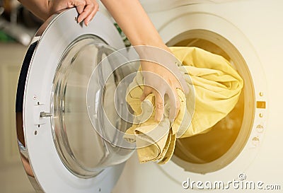 Hands female getting in dirty clothes into washing machine doing laundry at house Stock Photo