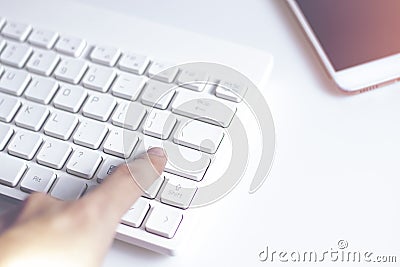 Hand finger push on enter keyboard button and mobile phone on white background in network business Stock Photo
