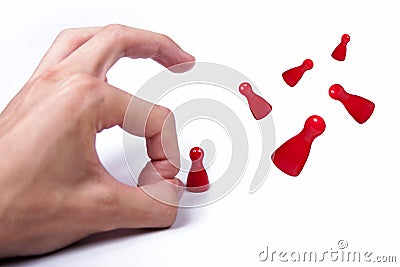 Hand flicking away small red game pieces Stock Photo