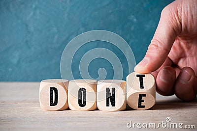 Hand flips a cube with letters, changing the word DON`T into DONE Stock Photo