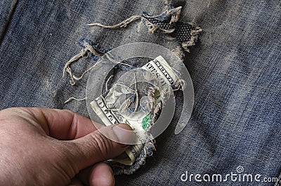 Hand gently pulls American Dollars out of ripped jeans Stock Photo