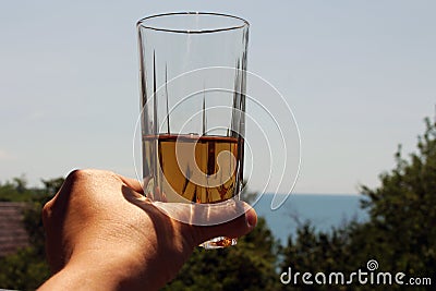 In the hand of the girl Apple juice in the glass. on the background of the sky. Stock Photo