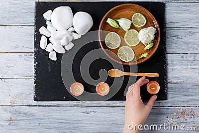 The hand of a girl makes a layout of items for spa procedures on a dark board. Stock Photo