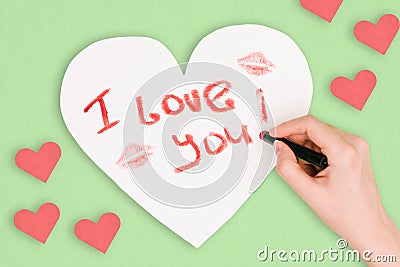 Hand girl writes lipstick love letter on Valentine`s Day. Handmade greeting card in the shape of a heart. Female kiss on Stock Photo