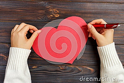 Hand of girl writing love letter on Valentine Day. Handmade red heart postcard. Woman write on postcard for 14 February holiday ce Stock Photo