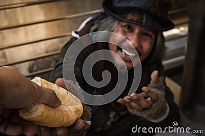 Hand giving bread or food to make hungry homeless man have happy face Stock Photo