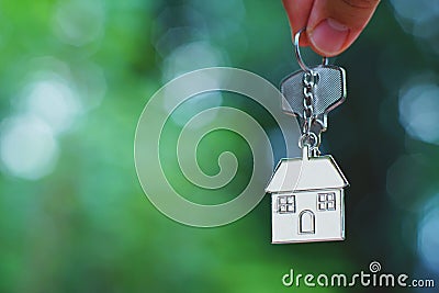 Hand giving home key with love house keyring with blur green garden, background, sweet home concept Stock Photo
