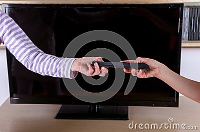 Hand giving the remote control to another hand Stock Photo