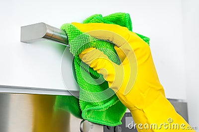 Hand in glove with green rag is cleaning stainless steel handles Stock Photo