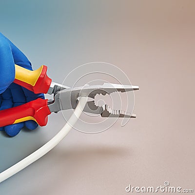 Hand in glove holds pliers electrician and cutting cable Stock Photo