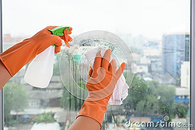 Hand in gloves cleaning window with rag and cleanser spray at ho Stock Photo