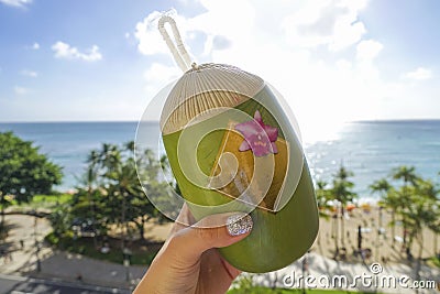 Hand grabbed a coconut-shaped container on the background of waikiki beach, O`ahu, Hawaii Stock Photo