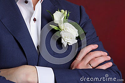 The hand of the groom with a ring and a buttonhole on the blue suit Stock Photo