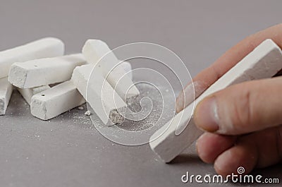 The hand of a grown man takes a piece of chalk lying on a gray b Stock Photo