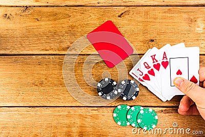 Hand having royal flush on wooden background, poker chips, dealer, gambler, poker concept Stock Photo