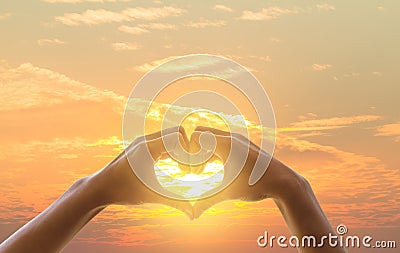 Hand on heart sunset background. The light filtering through the heart Shows love Stock Photo