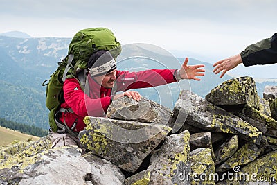 Hand helping hiker to climb the mountain Stock Photo