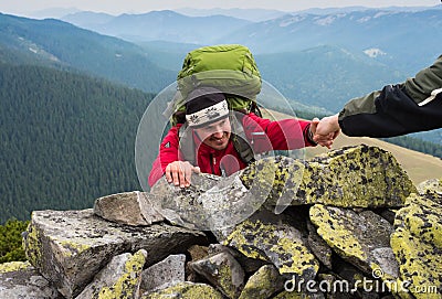 Hand helping hiker to climb the mountain Stock Photo