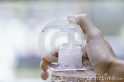 Hand hold algohol gel by use thumb nail pushing pumping head of the bottle and end of tube is dripping gel. Concept of hygine and Stock Photo