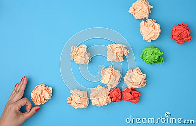 Hand hold crumpled sheets of colored paper on a blue background. Solution concept, brainstorming Stock Photo