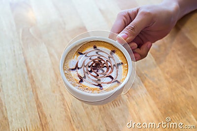 Hand hold a Cup of Coffee on wooden background Stock Photo