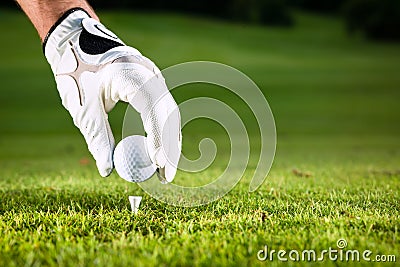 Hand hold golf ball with tee on course Stock Photo