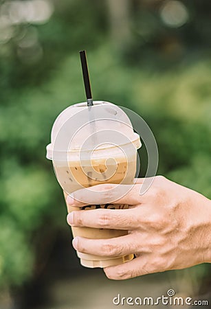 Hand hold iced latte coffee in a glass. cold summer drink background Stock Photo