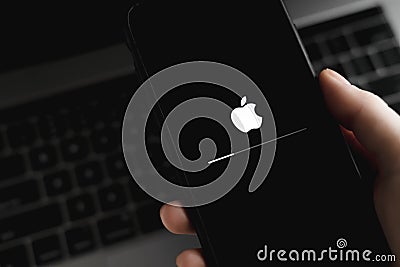 Hand hold the iPhone with iOS firmware update process on the screen Editorial Stock Photo
