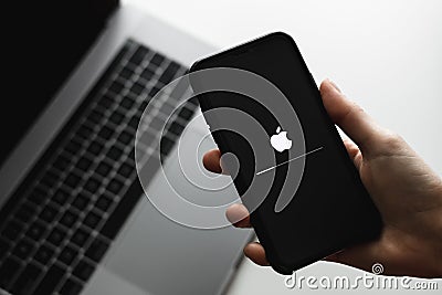 Hand hold the iPhone with iOS firmware update process on the screen Editorial Stock Photo