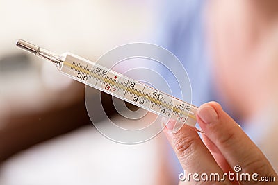 Hand holding analog medical thermometer Stock Photo