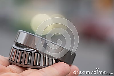 Hand holding Automotive wheel tapered roller bearing on road background, Car Maintenance Service Stock Photo