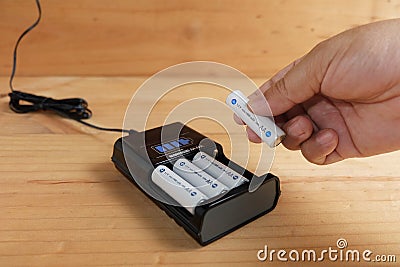 Hand holding battery size AA rechargeable with Charger Stock Photo