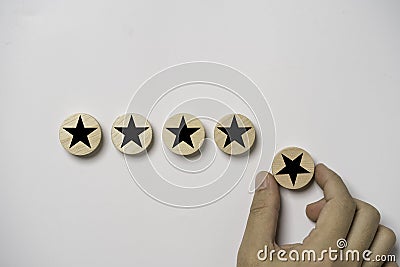 Hand holding black star which print screen on round wooden to give five stars for excellent evaluate after customer use product Stock Photo