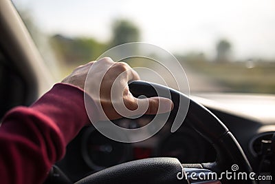 Hand holding on black steering wheel while driving in the car Stock Photo