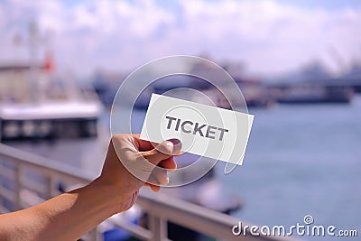 Hand holding blank mockup for ticket or card design, at a pier. Cruise ferry and ships in the background, defocused. Bright sunny Stock Photo