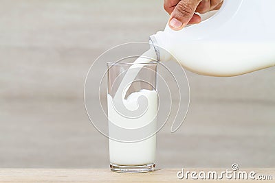 Hand holding bottle of fresh milk pouring into drinking glass Stock Photo