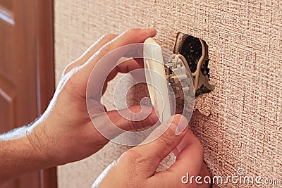 Hand holding a broken outlet, risking electric shock Stock Photo