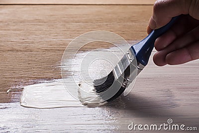 Hand holding a brush applying varnish paint Stock Photo