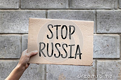 Hand holding cardboard with text STOP RUSSIA. Anti-war protest. RUSSIAN WAR. Aggressive invasion Stock Photo