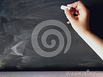 Hand holding chalk on blackboard. Stock Photo