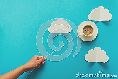 Hand holding coffee cup in shape of balloon on blue paper background. Toned Stock Photo