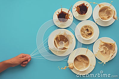 Hand holding coffee cups with milk and without in shape of balloons on blue paper background. Toned. Weather or good morning conce Stock Photo