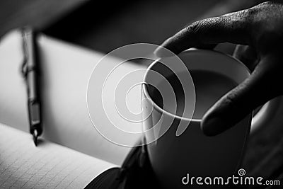 Hand holding a coffee mug with a journal Stock Photo