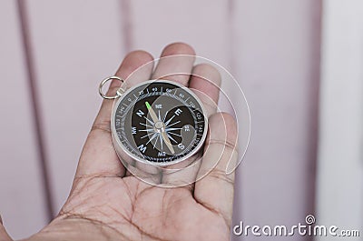 Hand holding compass over wooden wall Stock Photo