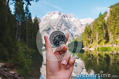 hand holding compass view of mountain lake on background Stock Photo